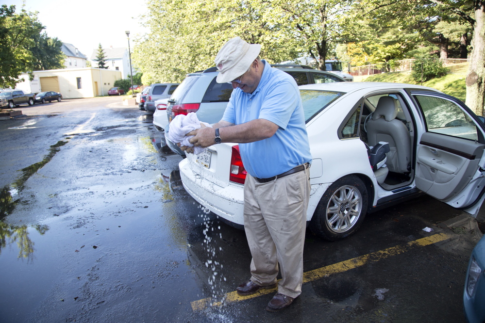 Martin Spechler of Bloomington, Ind., wrings out a towel as he sops up water from the back seat of his car Thursday. His vehicle was among dozens damaged by flooding at the La Quinta Inns & Suites in Portland.