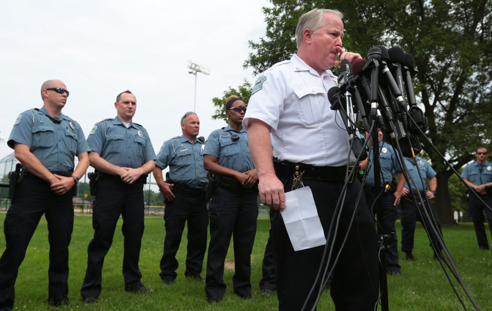 Ferguson Police Chief Tom Jackson is surrounded by his officers at a news conference Friday. Jackson took questions from the media after identifying Darren Wilson as the officer who shot Michael Brown.
