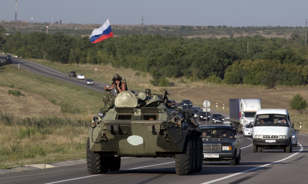 A Russian military vehicle maneuvers on a road behind a convoy of aid trucks, 9 miles from the Ukrainian border in the Rostov-on-Don region, Russia, on Friday. The Ukraine president says his forces engaged with Russian vehicles in Ukraine.