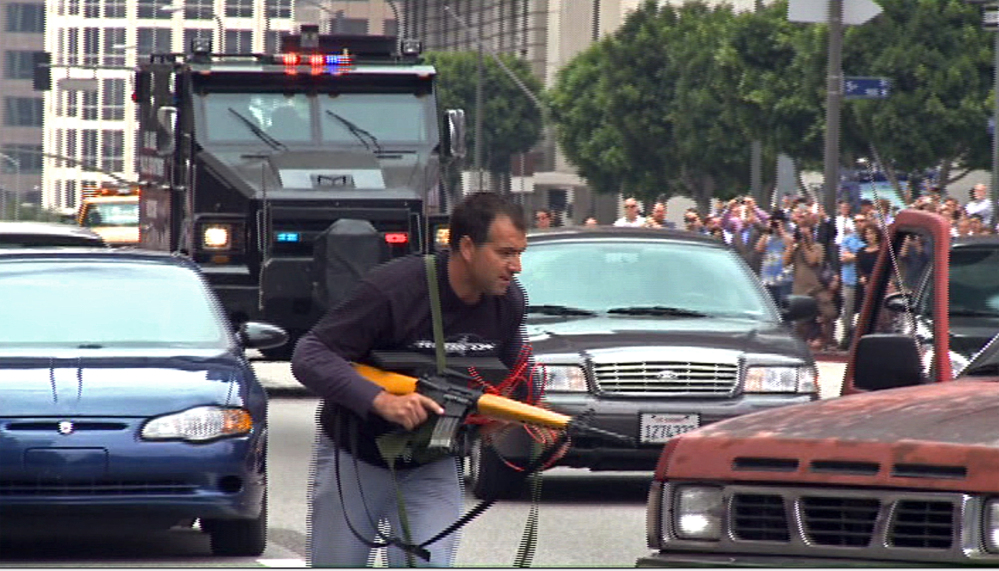 In this July 6, 2013, still frame from a video produced by the Los Angeles Police Department, a man posing as a terrorist runs as a heavily-armored vehicle approaches in a drill simulating a terrorist attack in downtown Los Angeles. The Associated Press
