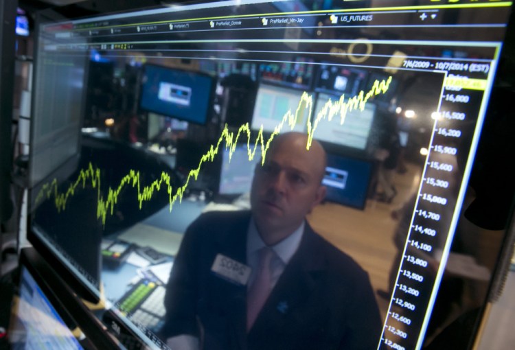 Specialist Jay Woods is reflected July 3 in a screen at his post that shows five years of the Dow Jones industrial average, on the floor of the New York Stock Exchange.