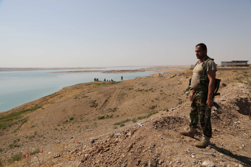 A Kurdish peshmerga fighter stands guard near the Mosul Dam at the town of Chamibarakat outside Mosul, Iraq, Sunday.