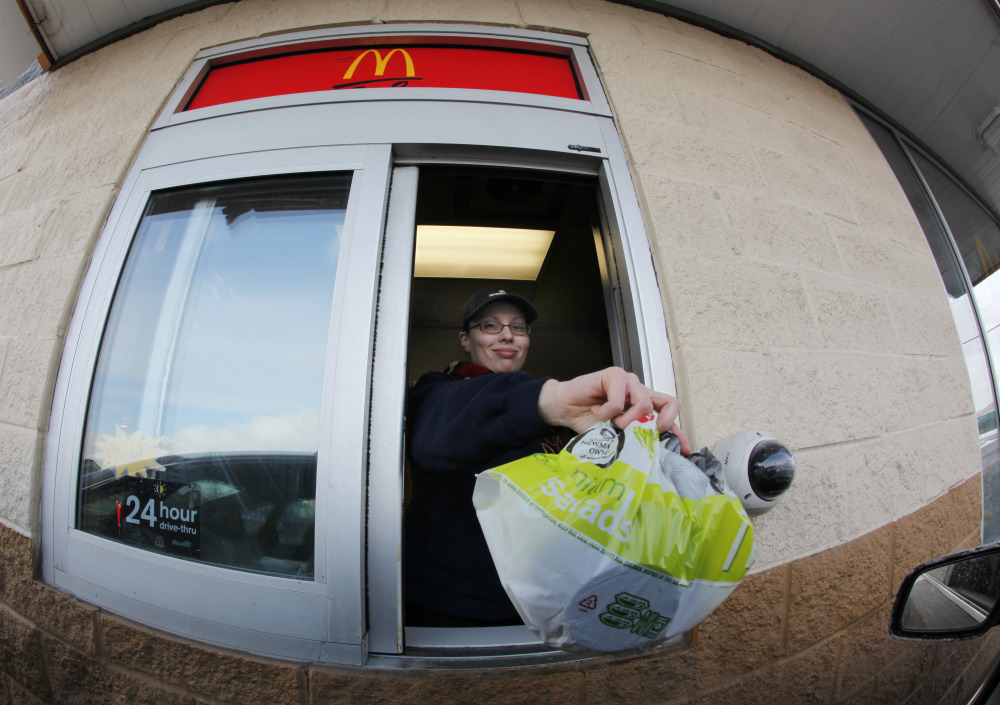 McDonald’s employee Cortney Sobowiec hands a patron a salad at the drive up window at McDonalds in Williamsville, N.Y.