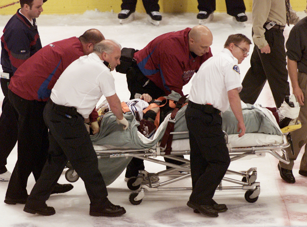 Steve Moore of the Colorado Avalanche is taken off the ice after being hit by the Vancouver Canucks’ Todd Bertuzzi on March 8, 2004. A settlement has been reached in Moore’s lawsuit against Bertuzzi for his career-ending hit.