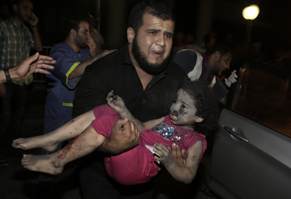 A Palestinian man carries an injured girl into the Shifa hospital after Israeli strikes that hit Gaza City on Tuesday. 