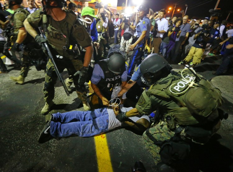 Police handcuff a protester after rushing the crowd to arrest him on West Florissant Avenue in Ferguson, Mo. early Wednesday.