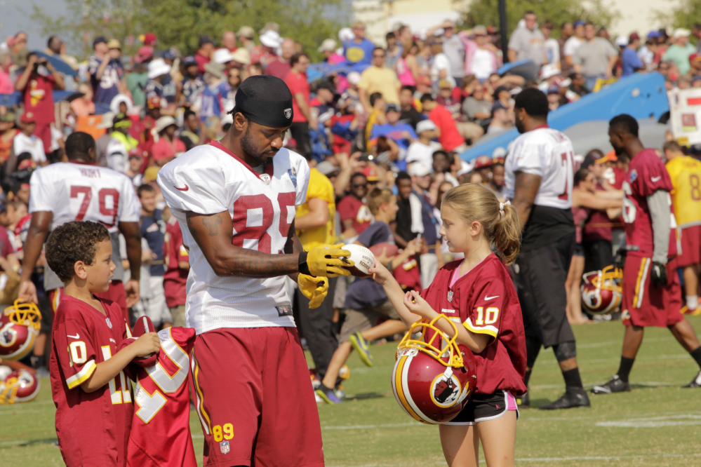 Santana Moss (89) of Washington’s NFL team signs autographs with Kaya Todd, 9, right, and Devin Wright, 7, after a joint practice with the New England Patriots in Richmond, Va. In the time-warped world of professional sports, anything past 30 opens conversations about players being past their prime. If you get to 35, well, then the geriatric jokes start flying.