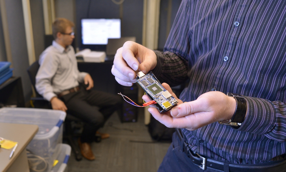 Michael Guesev, left, works at USM’s new Cyber Security Lab at the Portland campus on Wednesday as Samuel Barton shows a micro computer used for data monitoring.