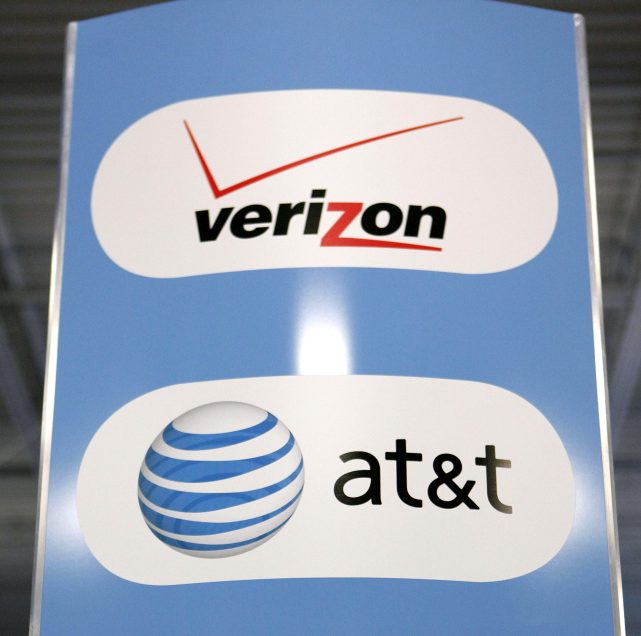 A sign for Verizon, AT&T and Sprint mobile phones is on display at a Best Buy store. Carriers are trying to lure customers with new offerings.