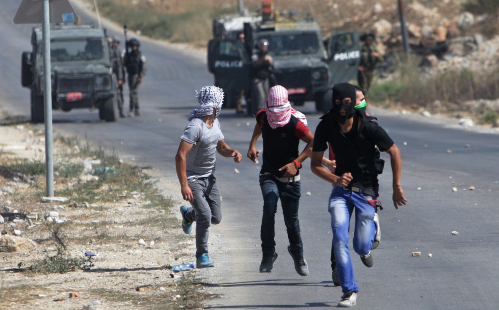 Palestinian protesters run away from Israeli soldiers during clashes following a demonstration against the Israeli military action in Gaza, in the West Bank city of Nablus on Friday.