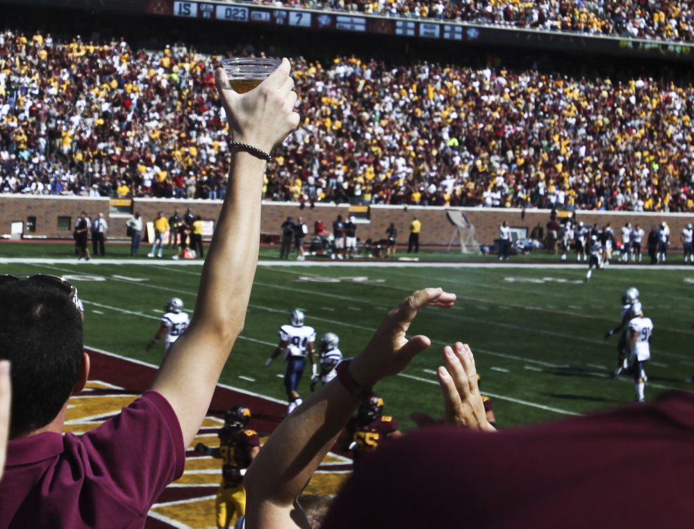 A football fan hoists a beer during a college game between Minnesota and New Hampshire at TCF Bank Stadium in Minneapolis, Minn., in September 2012. A growing number of revenue-starved schools are bringing the party inside, opening taps in concourses that traditionally have been alcohol-free zones.