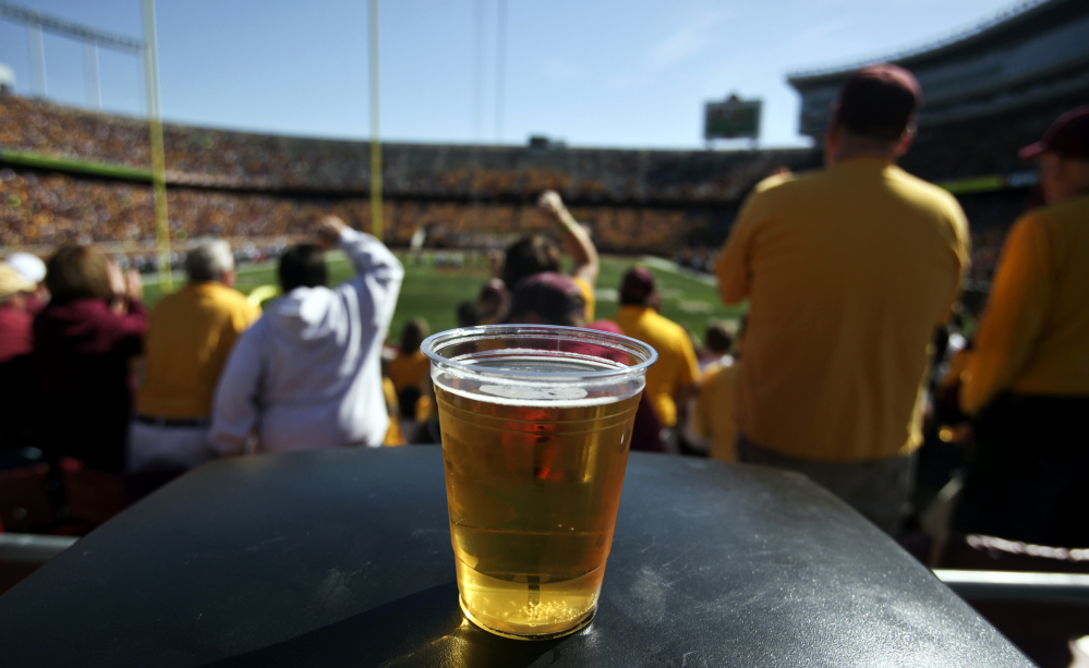 A beer sits atop a garbage can as Minnesota college football fans cheer a play against New Hampshire at TCF Bank Stadium in Minneapolis, Minn., in September 2012. A growing number of schools are capitalizing on fans’ taste for the suds.