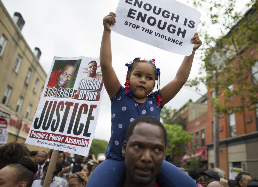 Ameariah Shearin holds a sign atop her father Theodore during a Saturday march through Staten Island.