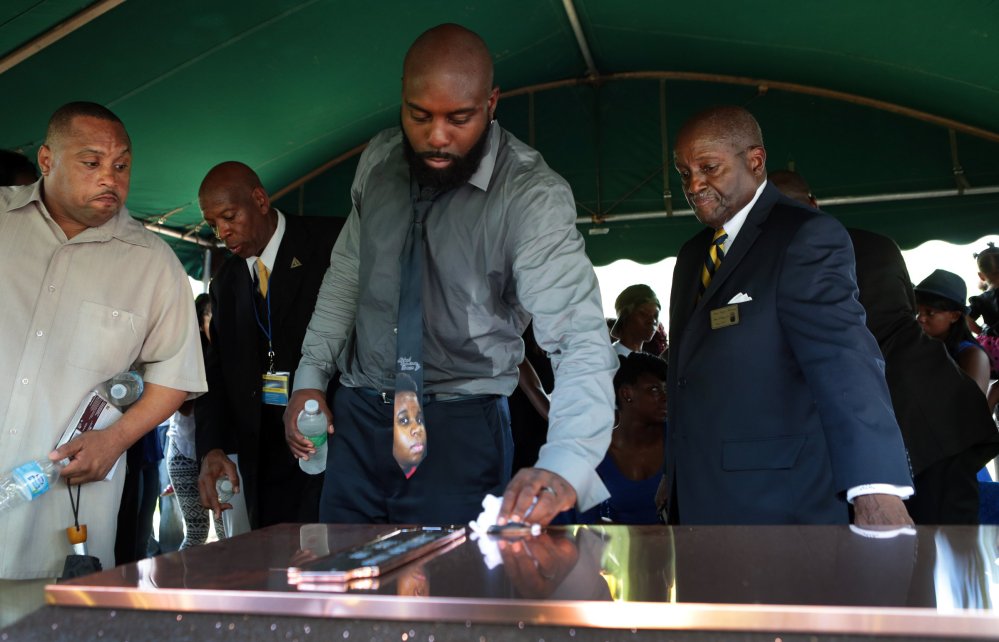 Michael Brown, Sr. wipes the top of the vault containing the casket of his son Michael Brown, Monday in Normandy, Mo. Hundreds of people gathered to say goodbye to Brown, who was shot and killed by a Ferguson, Mo., police officer on Aug. 9.