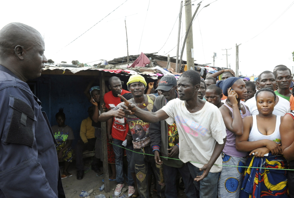 Residents, who are in an Ebola quarantine area, complain to a security officer as they wait for their relatives to bring them food and essentials, in West Point, Monrovia August 23, 2014. In an attempt to contain the virus, Liberia imposed a quarantine in West Point, a large slum in the capital Monrovia, on August 19. Security forces have been deployed to stop people from entering or leaving the area.