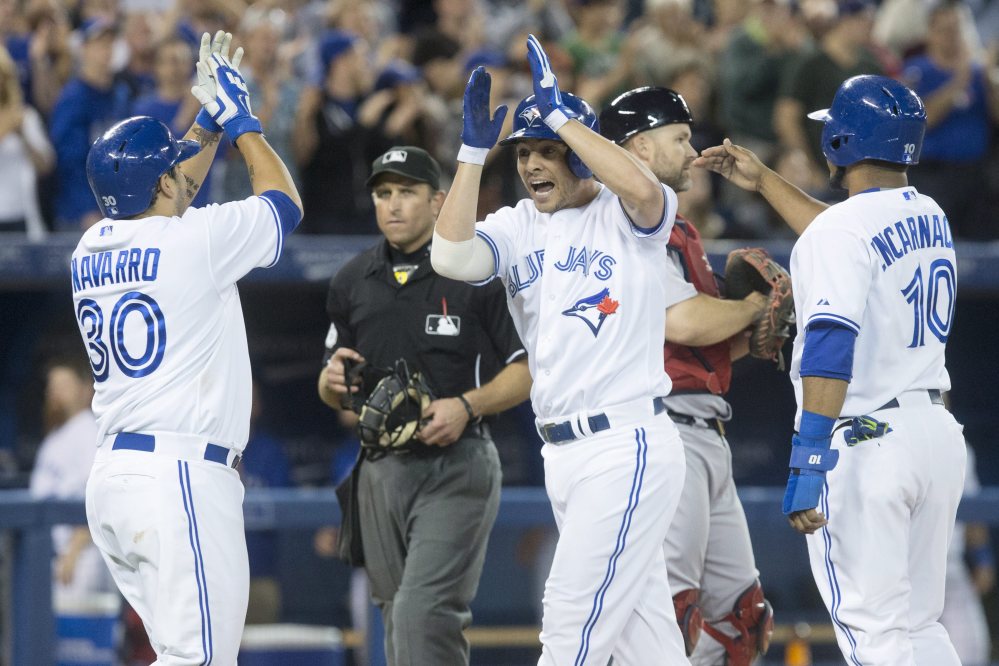Toronto Blue Jays’ Danny Valencia, center, celebrates with Dioner Navarro, left, and Edwin Encarnacion after hitting a three run homer off Boston Red Sox pitcher Junichi Tazawa during seventh inning American League baseball action in Toronto on Wednesday, Aug. 27, 2014. (AP Photo/The Canadian Press, Chris Young)