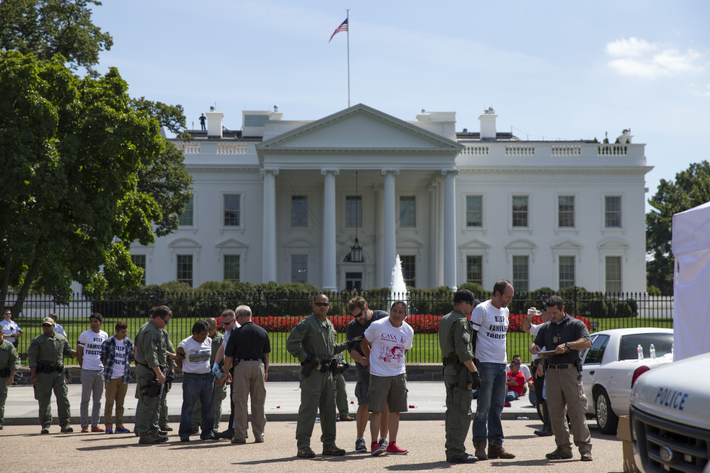 Demonstrators are lined up outside the White House on Thursday as they are arrested during a protest on immigration reform. Demanding a halt to deportations, protesters draped themselves in American flags and held signs saying, “I am a witness for justice” as onlookers cheered them on.