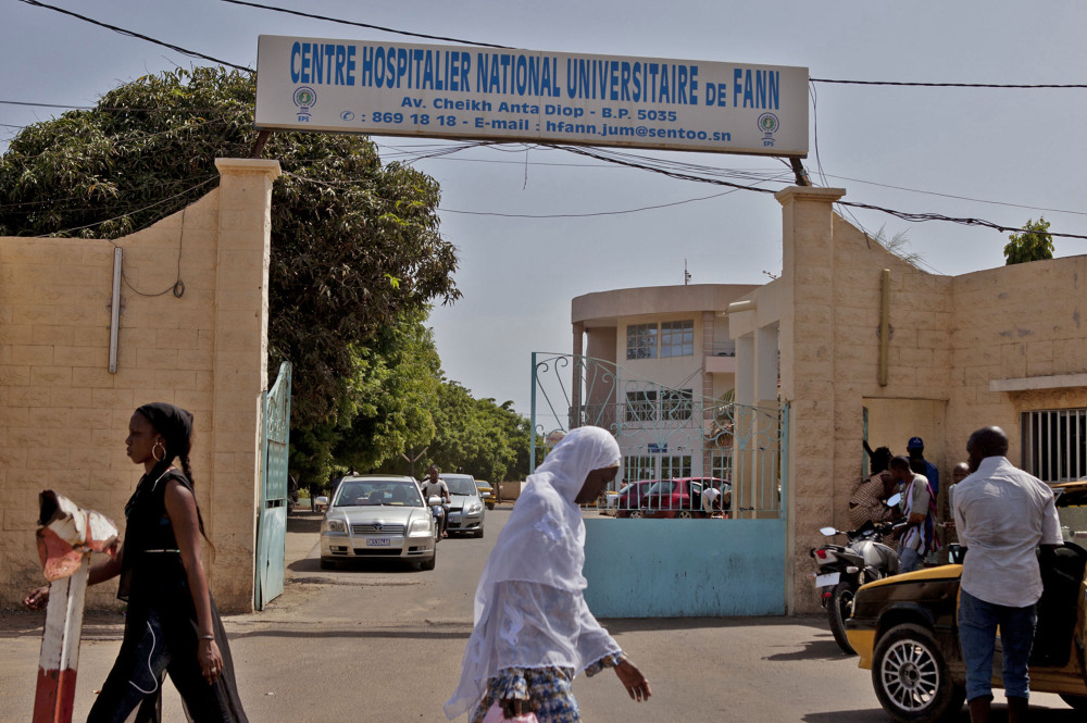 Women walk past the entrance to the University Hospital Fann, where a student is being treated for the Ebola virus, in Dakar, Senegal, on Friday.