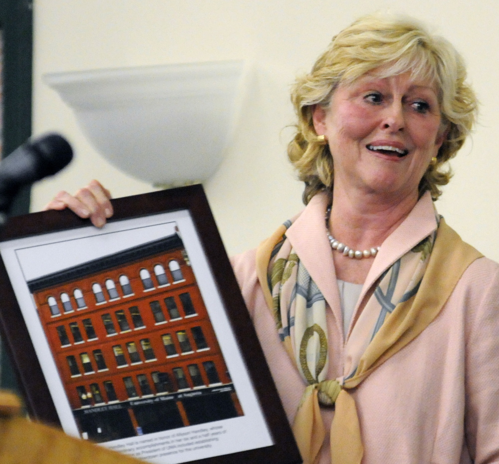University of Maine at Augusta President Allyson Handley holds up a framed photo after she found out Friday the school as renaming one of its buildings for her.