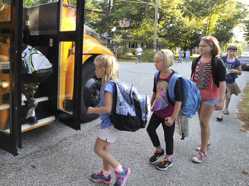 First grade students Elizabeth Baker, Neallie Morey, and Neallie’s sister Carly, a fifth-grader, were among RSU 14 students in Windham to board a school bus Tuesday for the first day back to school. John Patriquin/Staff Photographer
