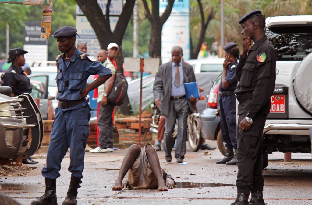 Guinea police secure the area around a man who collapsed in a puddle of water on the street, and people would not approach him as they fear he may be suffering from the Ebola virus in the city of Conakry, Guinea, on Wednesday. The man lay in the street for several hours before being taken to an Ebola control center for assessment. 