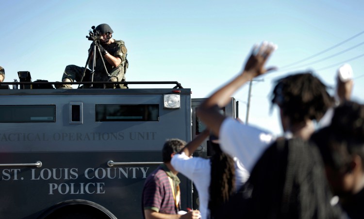 A member of the St. Louis County Police Department points his weapon in the direction of a group of protesters in Ferguson, Mo., on Wednesday as unrest continues over the fatal shooting of an unarmed black teenager.