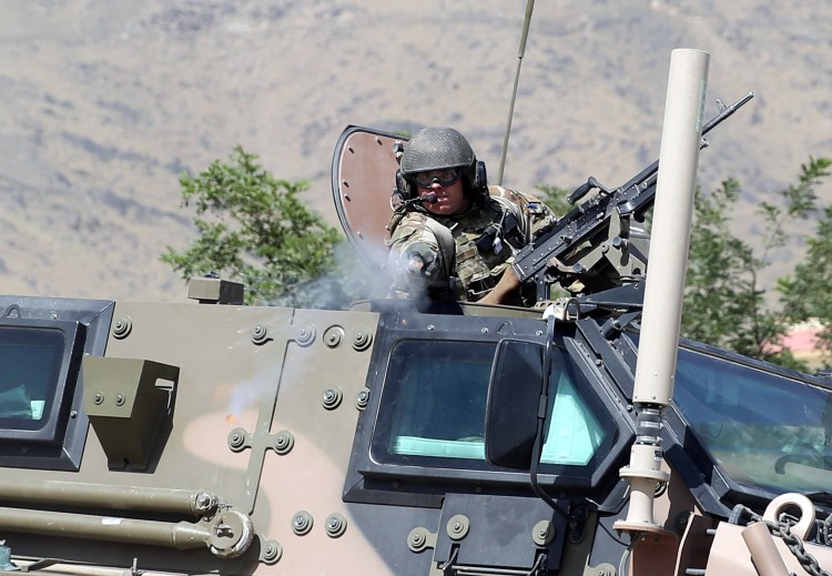 A NATO soldier opens fire in an apparent warning shot in the vicinity of journalists near the main gate of Camp Qargha, west of Kabul, Afghanistan, Tuesday. The Associated Press