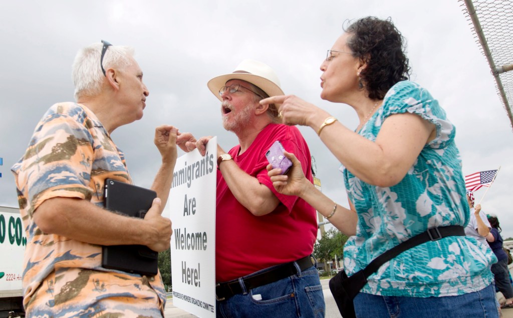 Reflecting the heated issue of the influx of children across the U.S. border, immigration supporters David Smith, center, and Rona Smith debate with a man opposed to illegal immigration on Saturday, in Conroe, Texas. The Associated Press