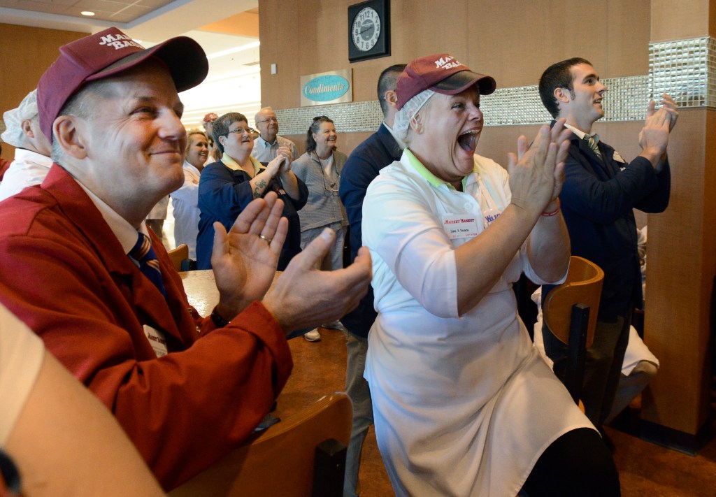 Lisa Lemieux, center right, from Salem, New Hampshire, gets emotional as workers watch their new owner, Arthur T. Demoulas, during a news conference on a TV at the Market Basket in Biddeford. 
