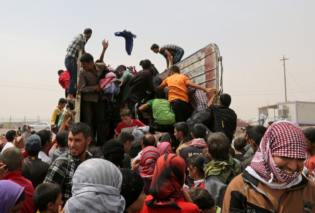 Displaced Iraqis gather to receive clothes provided by a charity at a camp  in Feeshkhabour, Iraq, on Tuesday. Some 1.5 million people have been displaced by fighting in Iraq since the Islamic State's rapid advance began in June, and thousands more have died. The Associated Press