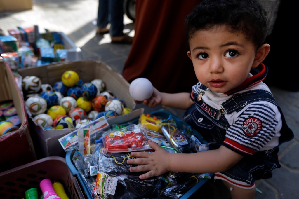A Palestinian child goes through toys at a vendor's stall in a market in Gaza City, northern Gaza Strip, on Wednesday as a cease-fire between Israel and Hamas that ended a month of fighting held for a second day. The Associated Press