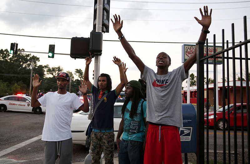 Protesters yell at police Monday, in Ferguson, Mo. The FBI opened an investigation Monday into the death of 18-year-old Michael Brown, who police said was shot multiple times Saturday after being confronted by an officer in Ferguson. The Associated Press