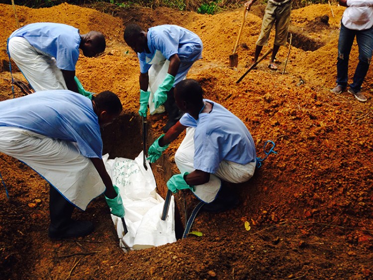 Volunteers lower a corpse, which is prepared with safe burial practices to ensure it does not pose a health risk to others and stop the chain of person-to-person transmission of Ebola, into a grave in Kailahun August 2. Reuters