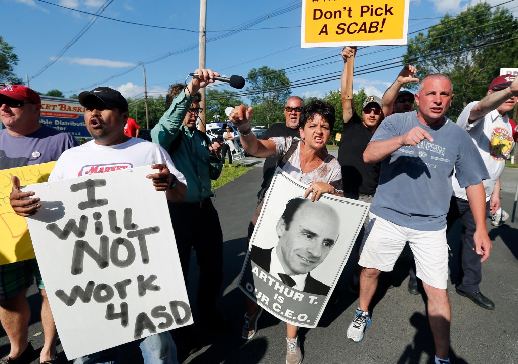 Protesters hold signs and taunt a car leaving the site of a Market Basket Supermarket job fair in Andover, Mass., on Aug. 6.