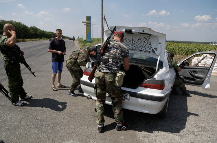Pro-Russian rebels search the car of a local resident at a checkpoint near the city of Donetsk, eastern Ukraine, Wednesday. Air strikes and artillery fire between pro-Russian separatists and Ukrainian troops in Donetsk have brought the violence closer than ever to the city center, as Kiev's forces move in on the rebel stronghold. The Associated Press
