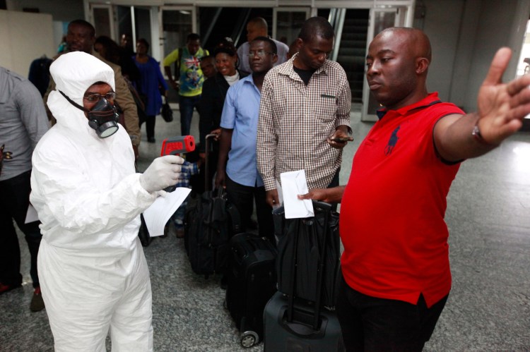 A Nigerian port health official uses a thermometer on a passenger at the arrivals hall of Murtala Muhammed International Airport in Lagos, Nigeria,  Wednesday. The Associated Press