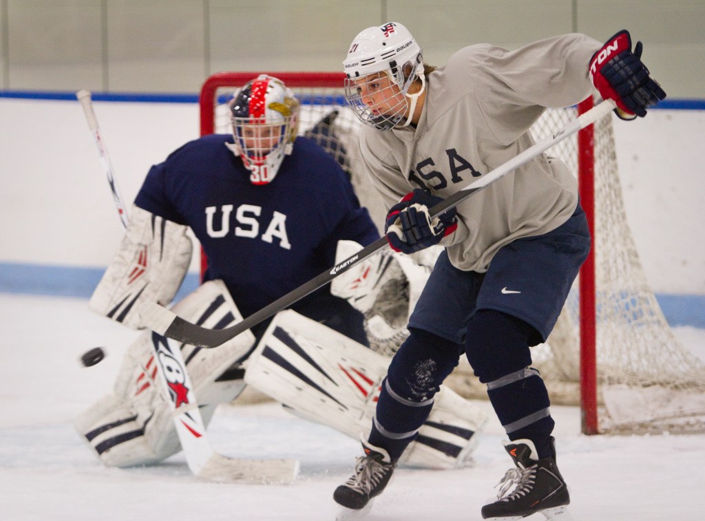 Hilary Knight, a member of the USA women’s hockey team, deflects the puck toward goalie Molly Schaus during a practice at the University of New England in Biddeford on Saturday.