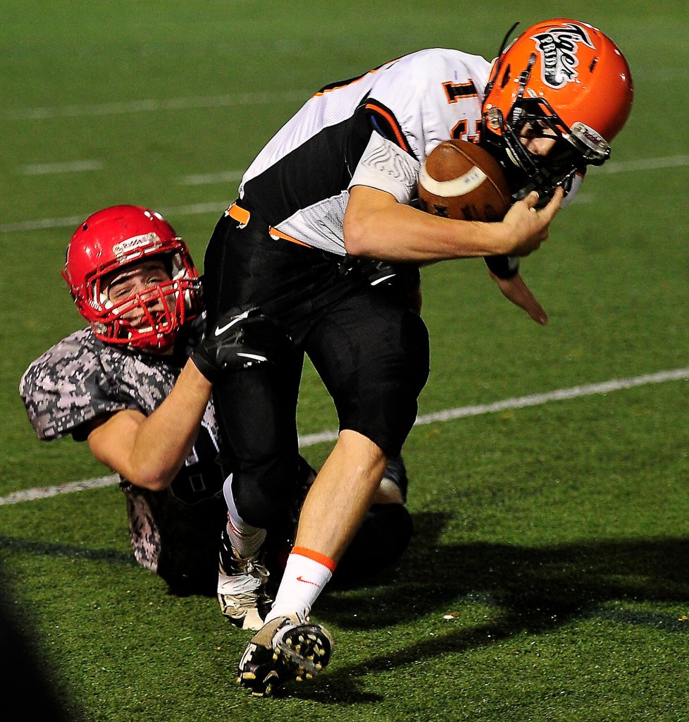 In this 2013 file photo,  Biddeford's Casey Twomey, gets dragged down by a Scarborough player. The Tigers' starting QB will be sidelined with an injury for the season's first game.