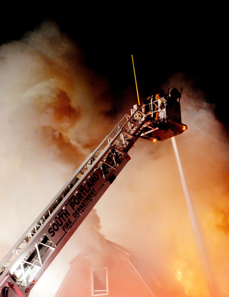 Firefighters spray water from above the flames at the Scarborough Commons building on Route 1 Monday night.