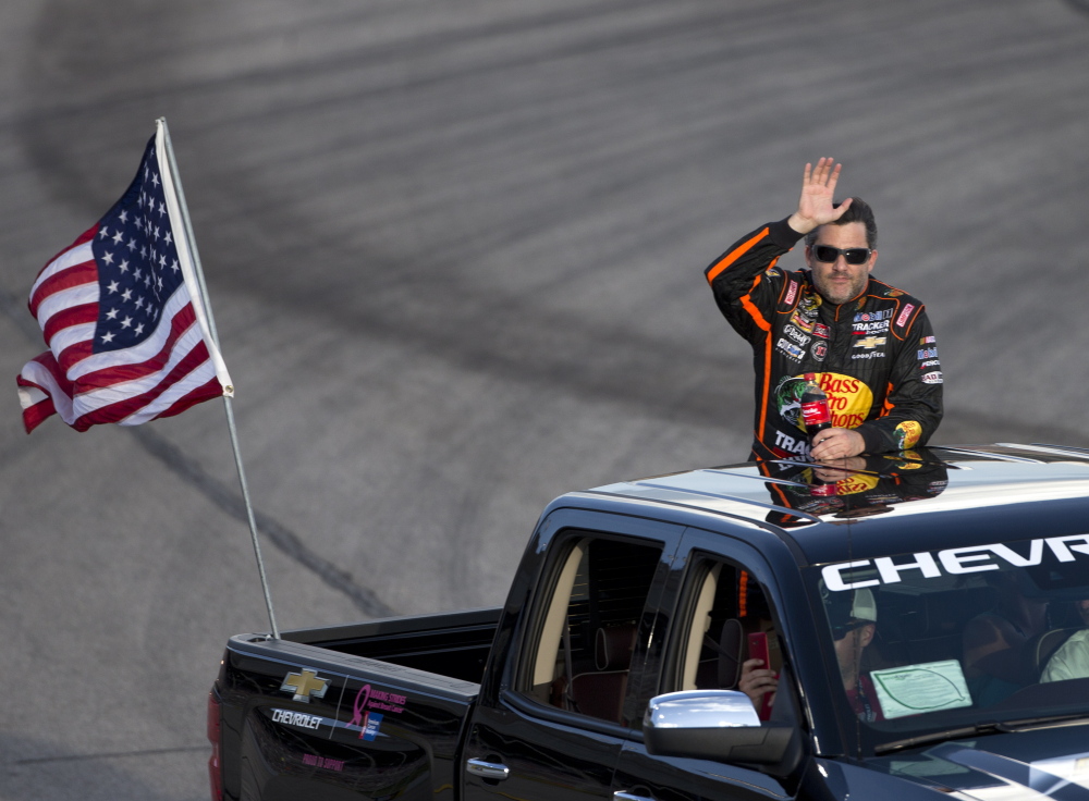 Tony Stewart waves to the crowd before the start of the Sprint Cup race Sunday night at Atlanta Motor Speedway. Stewart, in his first race since Aug. 3, didn’t complete the race because of two crashes and finished 41st.