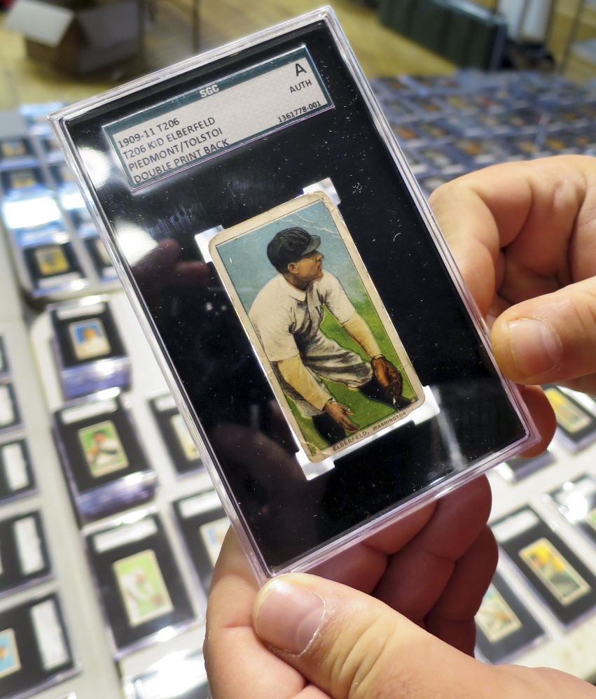 A 1909 baseball card depicting Kid Elberfeld is held by Troy Thibodeau at Saco River Auction Co. in Biddeford.