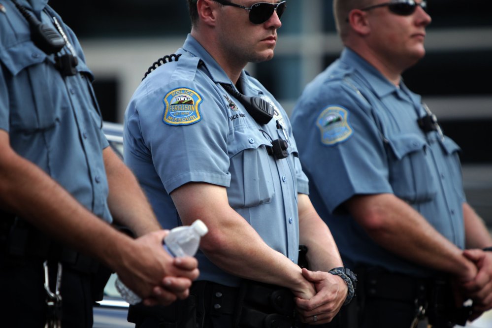 Police officers wear what appear to be body cameras as they hold the line against protesters during a rally in Ferguson, Mo., on Saturday.
