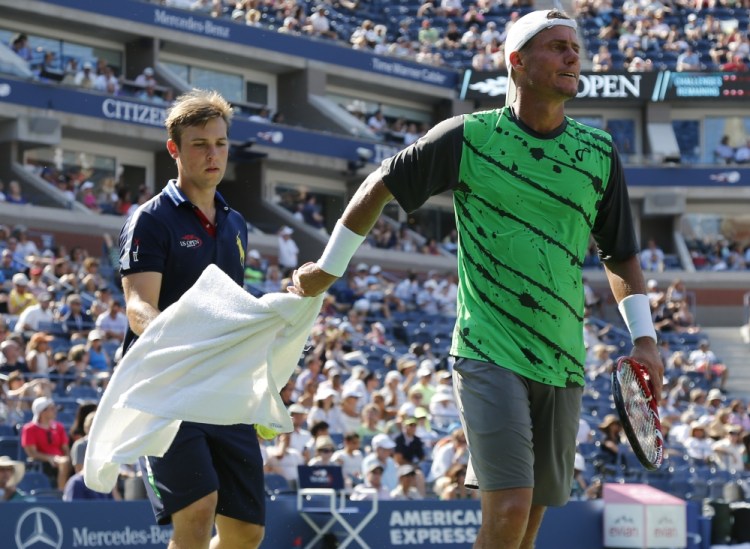 Lleyton Hewitt, of Australia, hands a towel back to a ball person after wiping sweat from his face and arms during the second round of the 2014 U.S. Open tennis tournament against.