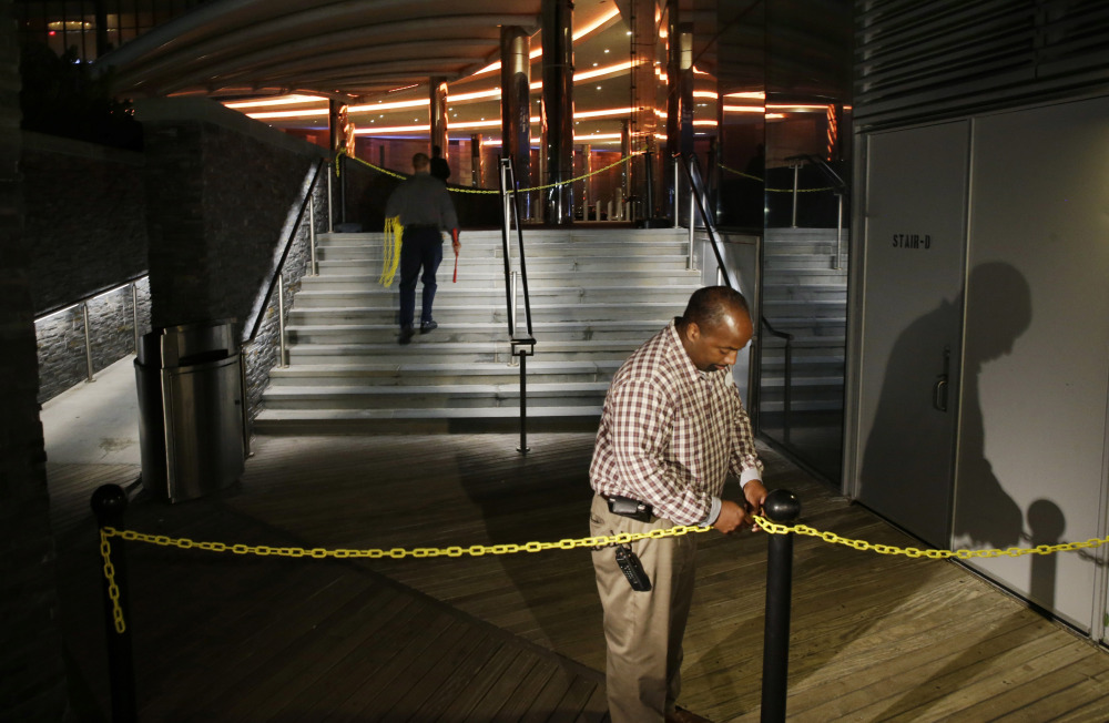 A casino worker secures a chain across The Boardwalk entrance to the Revel Hotel Casino early Tuesday in Atlantic City, N.J. The casino was supposed to enliven the gambling market but is a $2.4 billion boondoggle.