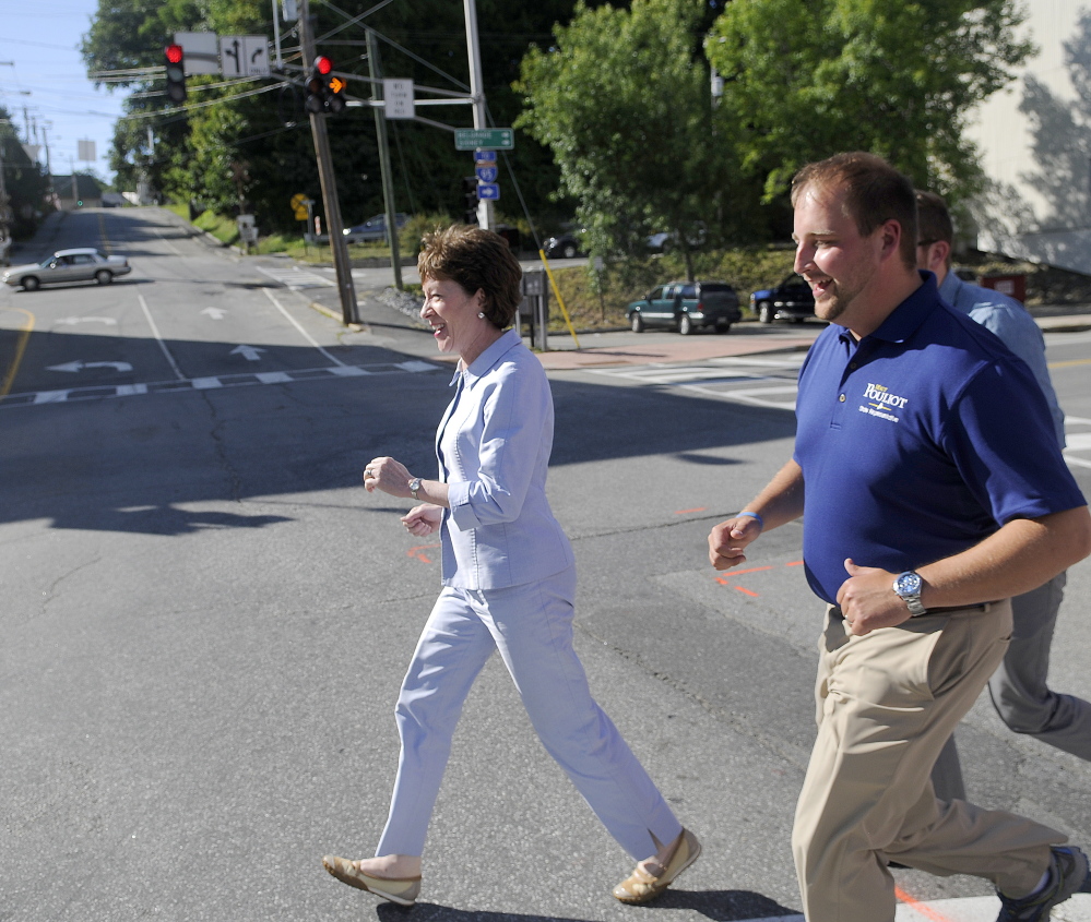 Sen. Susan Collins runs across Bridge Street in Augusta on Wednesday with state Rep. Matt Pouliot, R-Augusta, while campaigning in downtown Augusta.