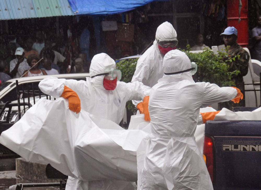 Health workers load the body of a man  suspected of dying from the Ebola virus onto the back of a truck on a busy street in Monrovia, Liberia, Tuesday. The number of deaths in West Africa has now surpassed 1,900.