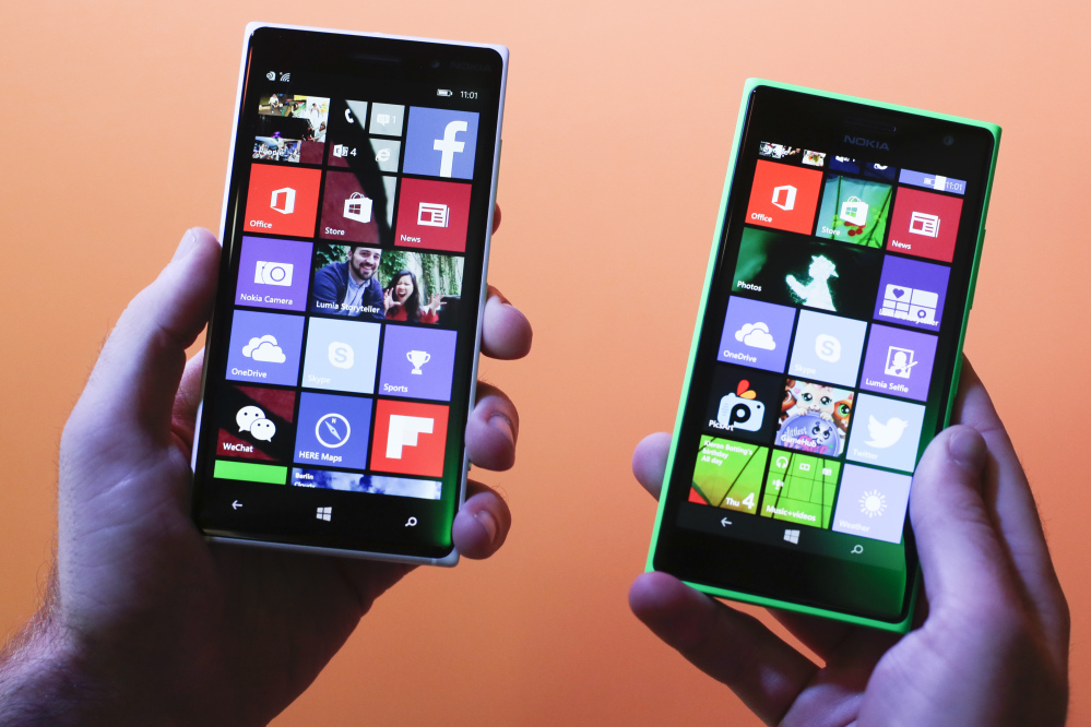 A man shows the new Lumia 830, left, and 730, right, smart phones during a Microsoft Nokia presentation event at the consumer electronic fair IFA in Berlin.