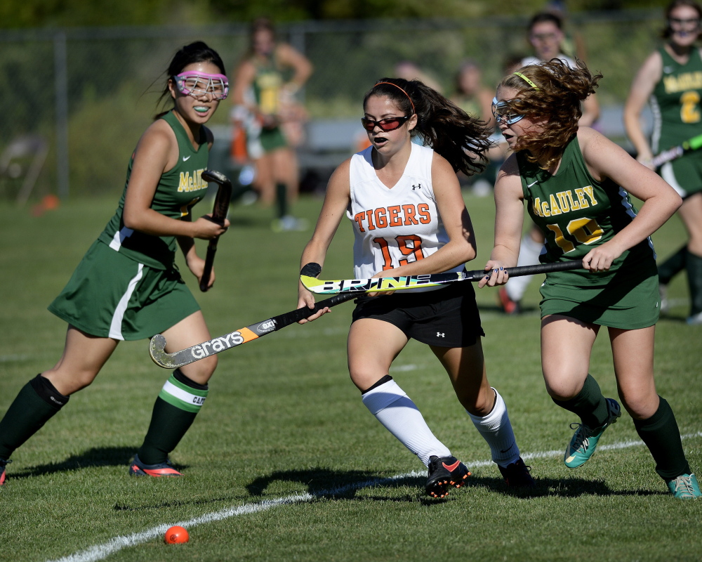 Mallory Mourmouras, center, who finished with four goals and two assists, competes for the ball with Sun Yool Park, left and Emma Spies of McAuley during their SMAA field hockey opener Thursday. Biddeford won at home, 14-0.
