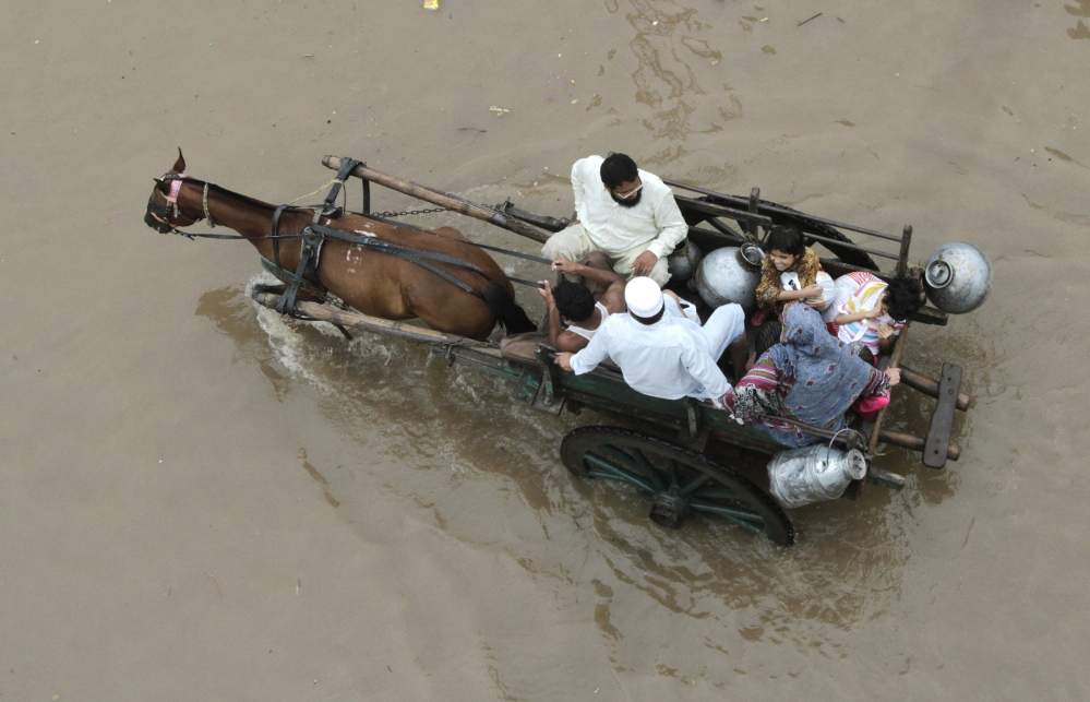 A Pakistani family travels through a flooded road after heavy rain in Lahore last week. The annual monsoon season has struck hard across Pakistan and in Indian-controlled areas of Kashmir, causing some of the worst flooding in decades.