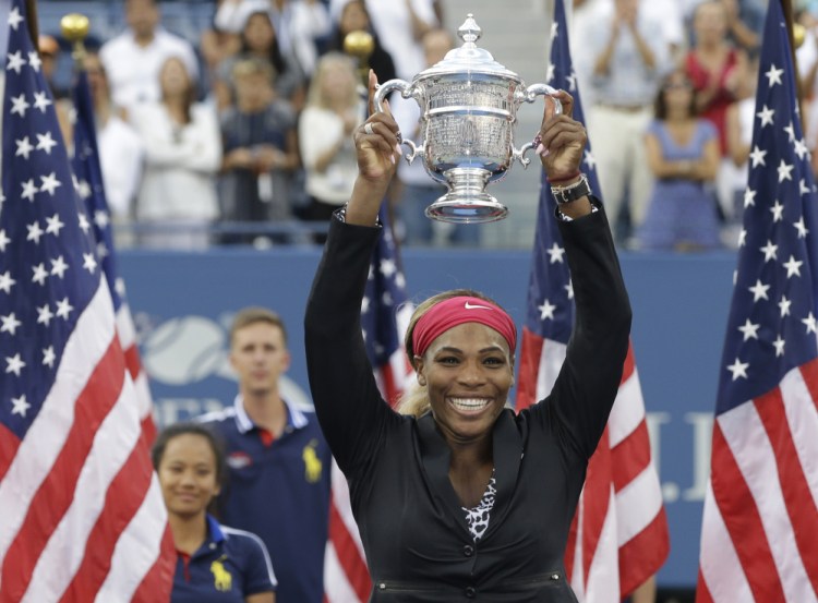Serena Williams, of the United States, holds up the championship trophy after defeating Caroline Wozniacki, of Denmark, during the championship match of the 2014 U.S. Open tennis tournament, Sunday in New York.